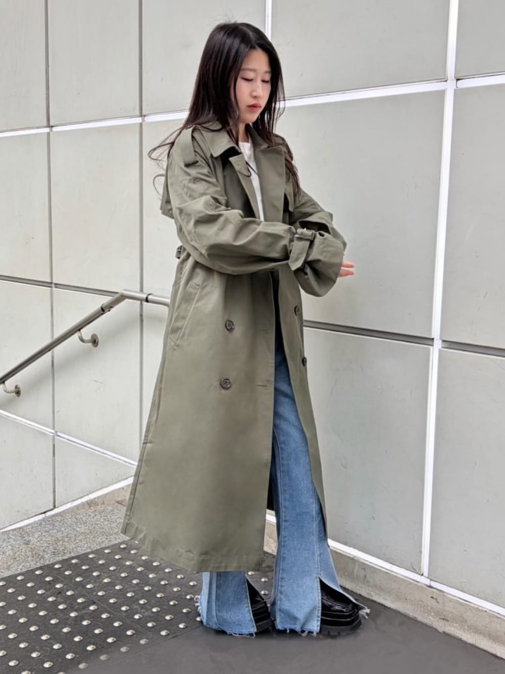 グリーン系のトレンチコート、ブルー系のデニムパンツ、ホワイト系のTシャツ/カットソーを着用したレディースの春コーディネートの3枚目の写真