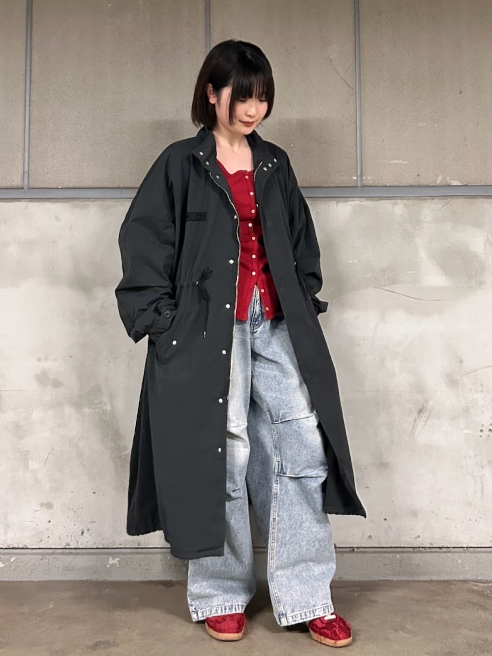 ブラック系のモッズコート、ブルー系のデニムパンツ、レッド系のカーディガン/ボレロを着用したレディースの春コーディネートの2枚目の写真