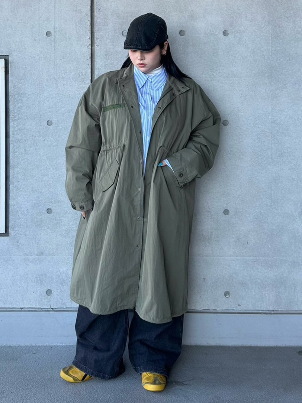 グリーン系のモッズコート、ブルー系のシャツ/ブラウス、ブラック系のデニムパンツを着用したレディースの春コーディネートの2枚目の写真