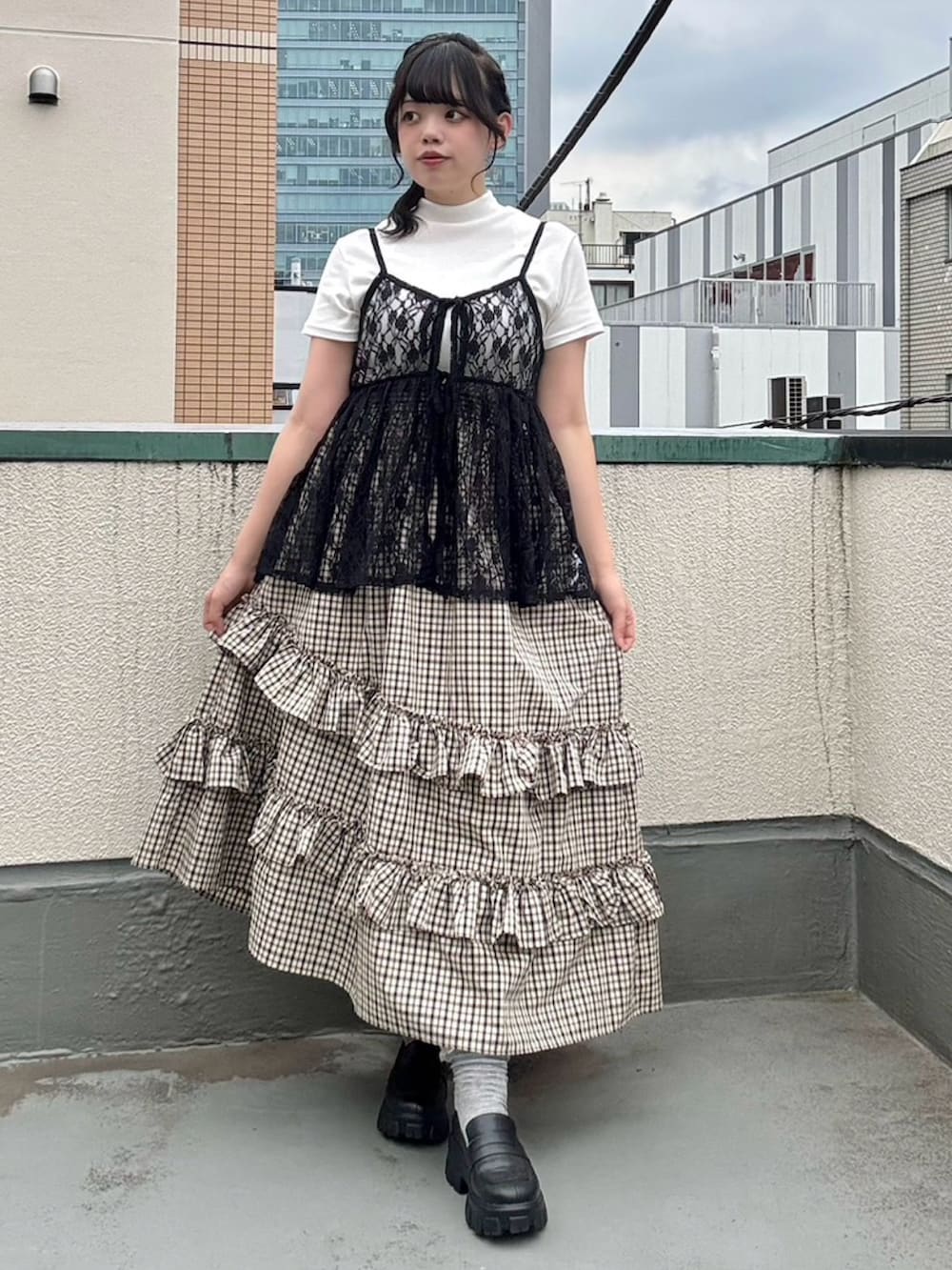 ベージュ系のスカート、ブラック系のチュニック、ホワイト系のTシャツ/カットソーを着用したレディースの夏コーディネートの2枚目の写真