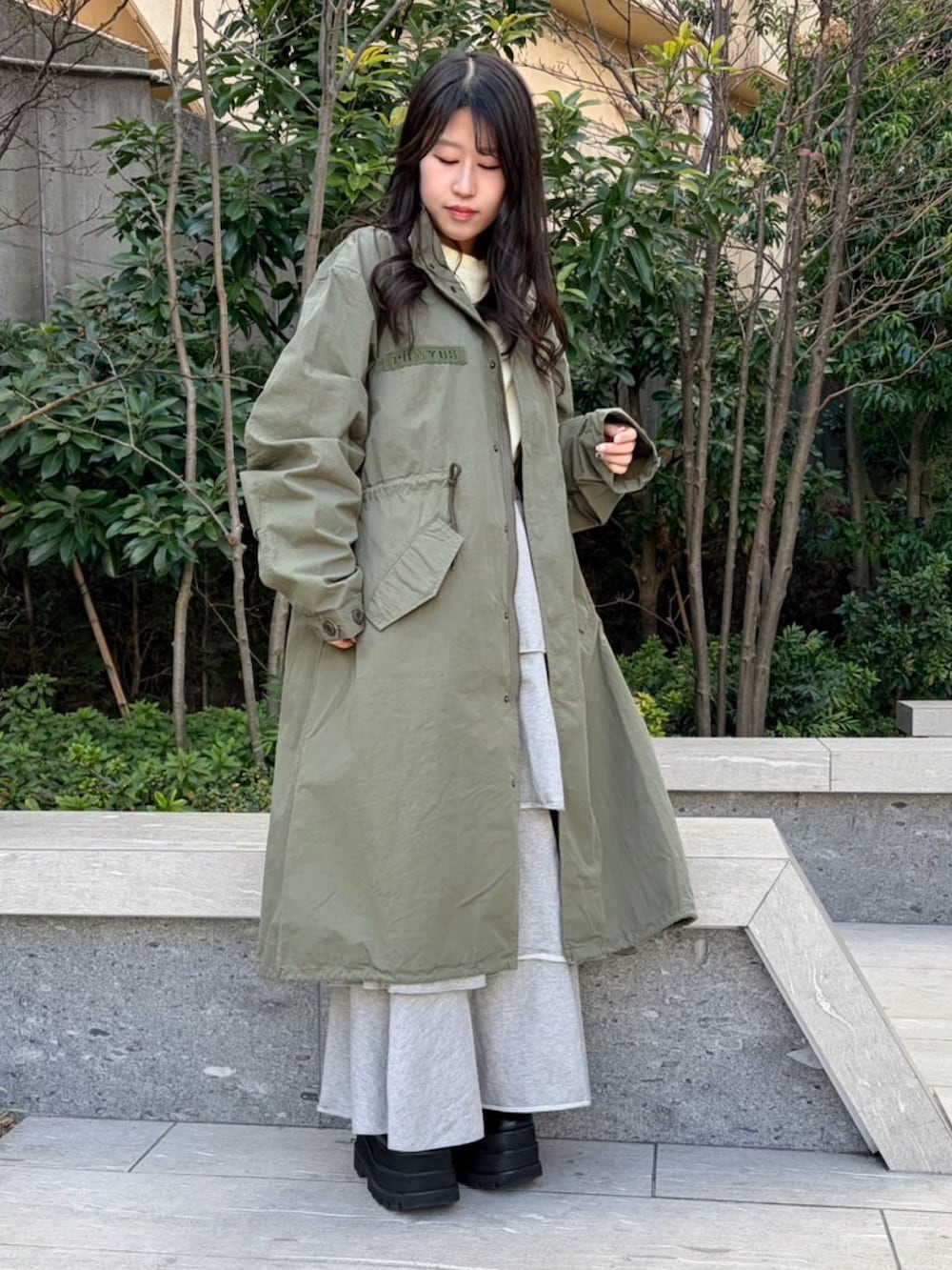 イエロー系のTシャツ/カットソー、グリーン系のモッズコート、グレー系のスカートを着用したレディースの冬コーディネートの2枚目の写真