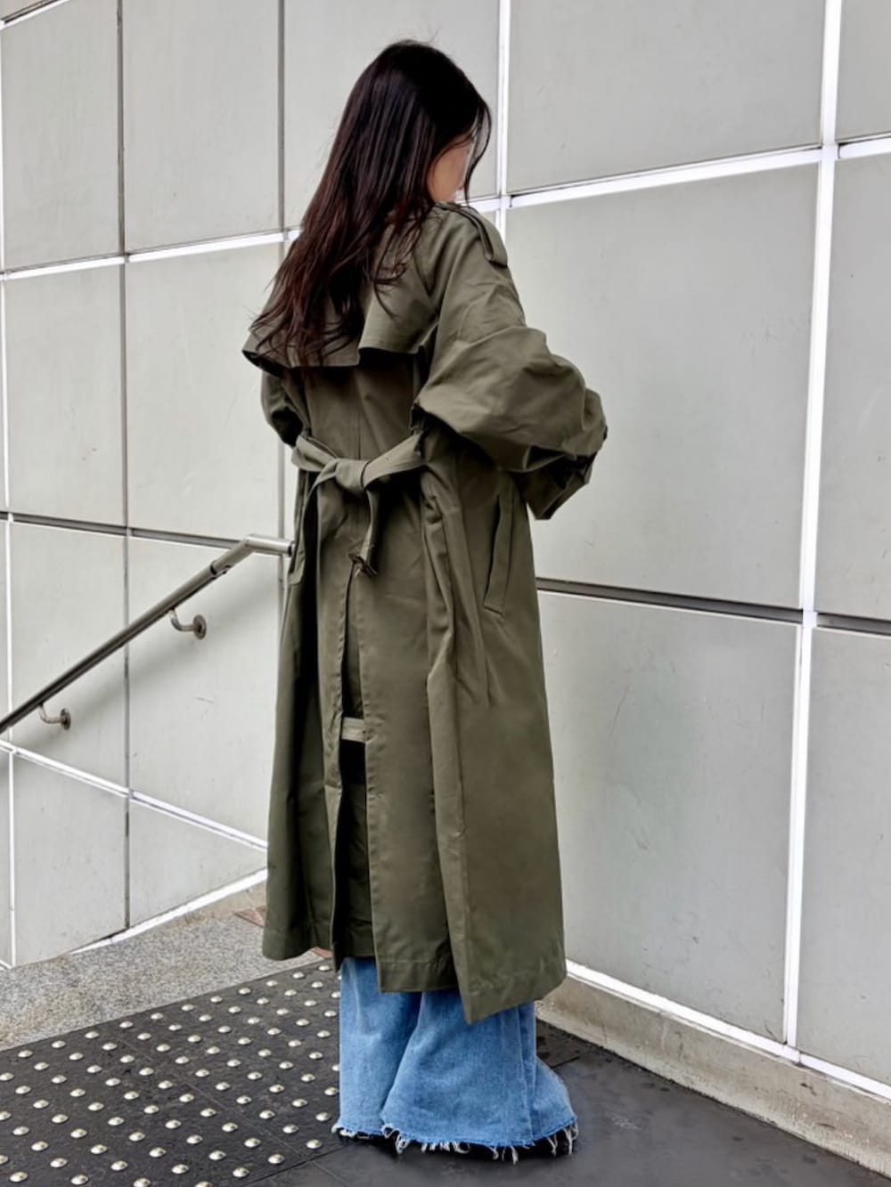 グリーン系のトレンチコート、ブルー系のデニムパンツ、ホワイト系のTシャツ/カットソーを着用したレディースの春コーディネートの5枚目の写真