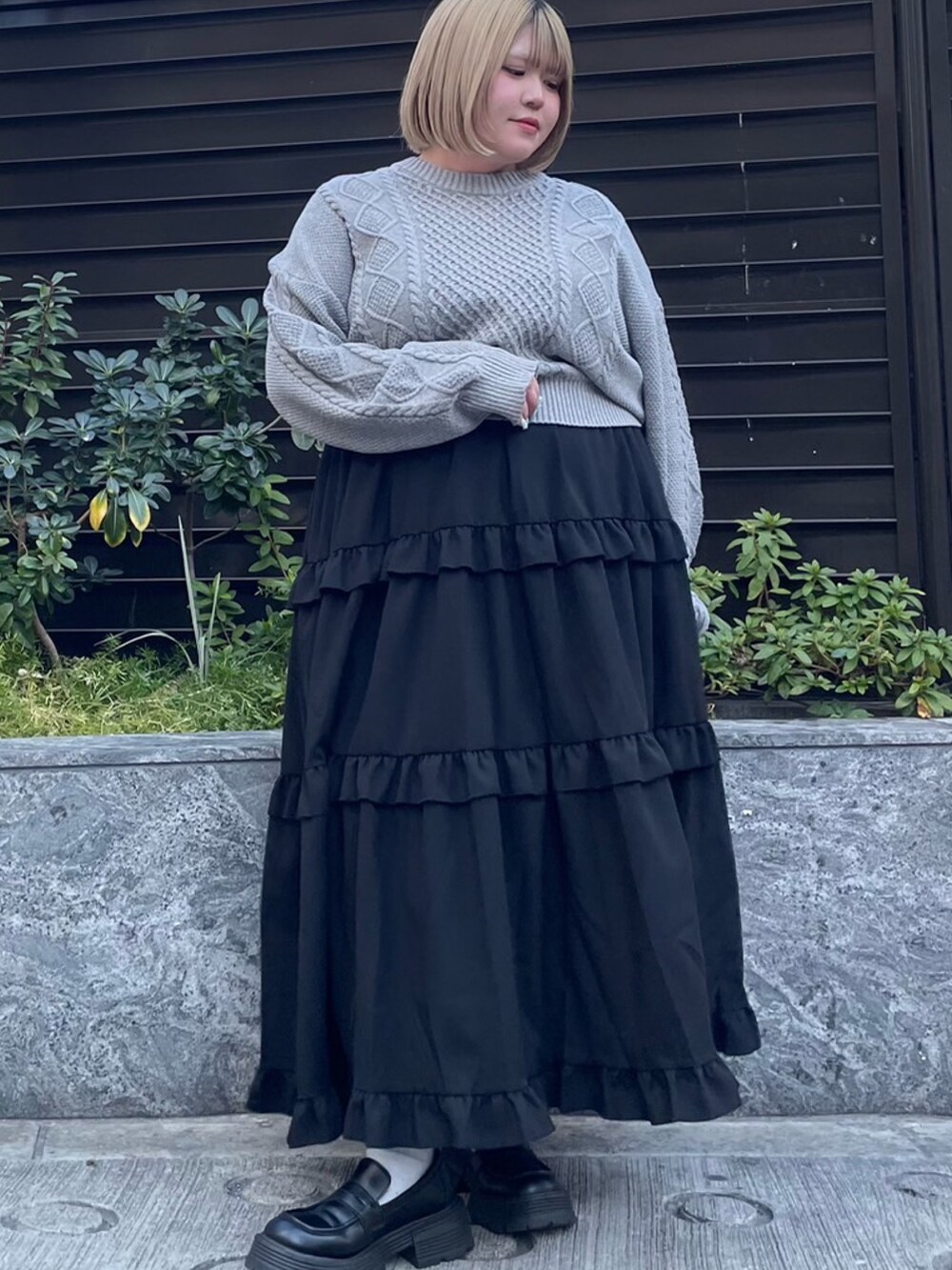 ブラック系のスカート、グレー系のニット/セーターを着用したレディースの冬コーディネートの2枚目の写真