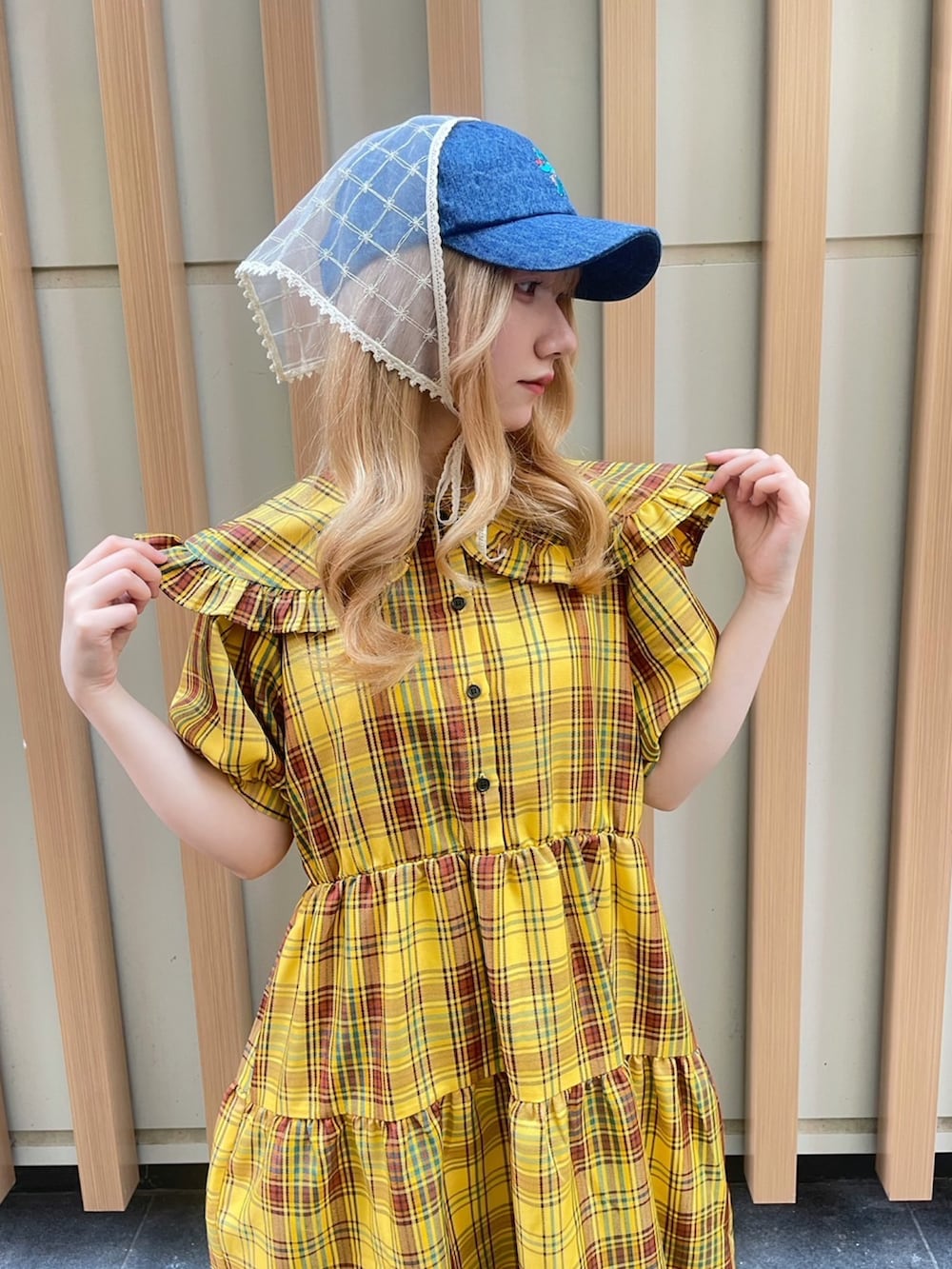 イエロー系のワンピース、ブルー系のキャップを着用したレディースの夏コーディネートの4枚目の写真