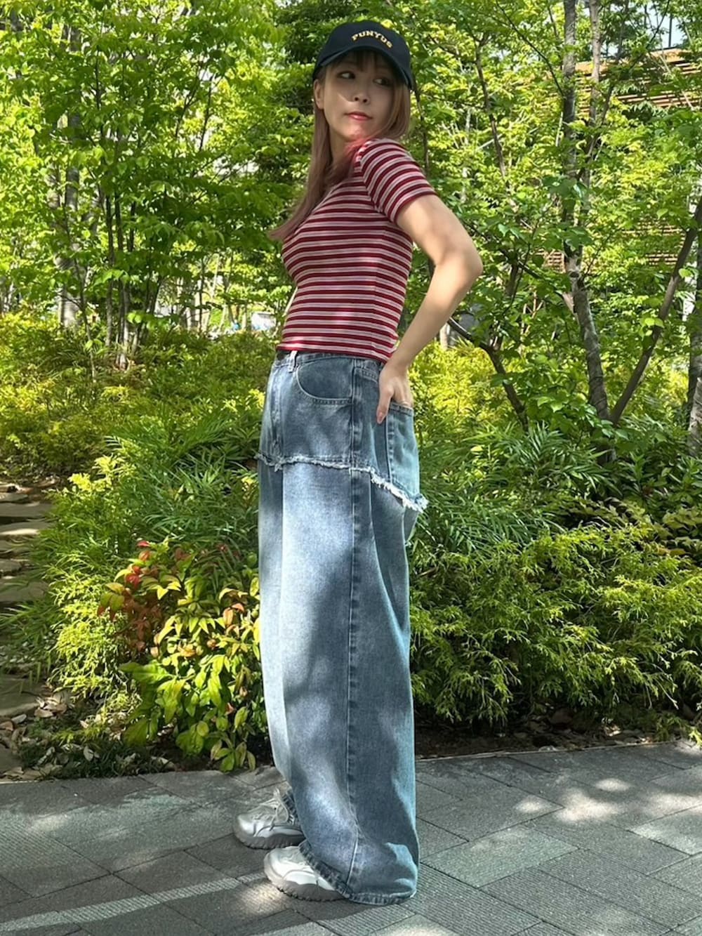 ブルー系のデニムパンツ、レッド系のTシャツ/カットソー、ブルー系のキャップを着用したレディースの春コーディネートの3枚目の写真