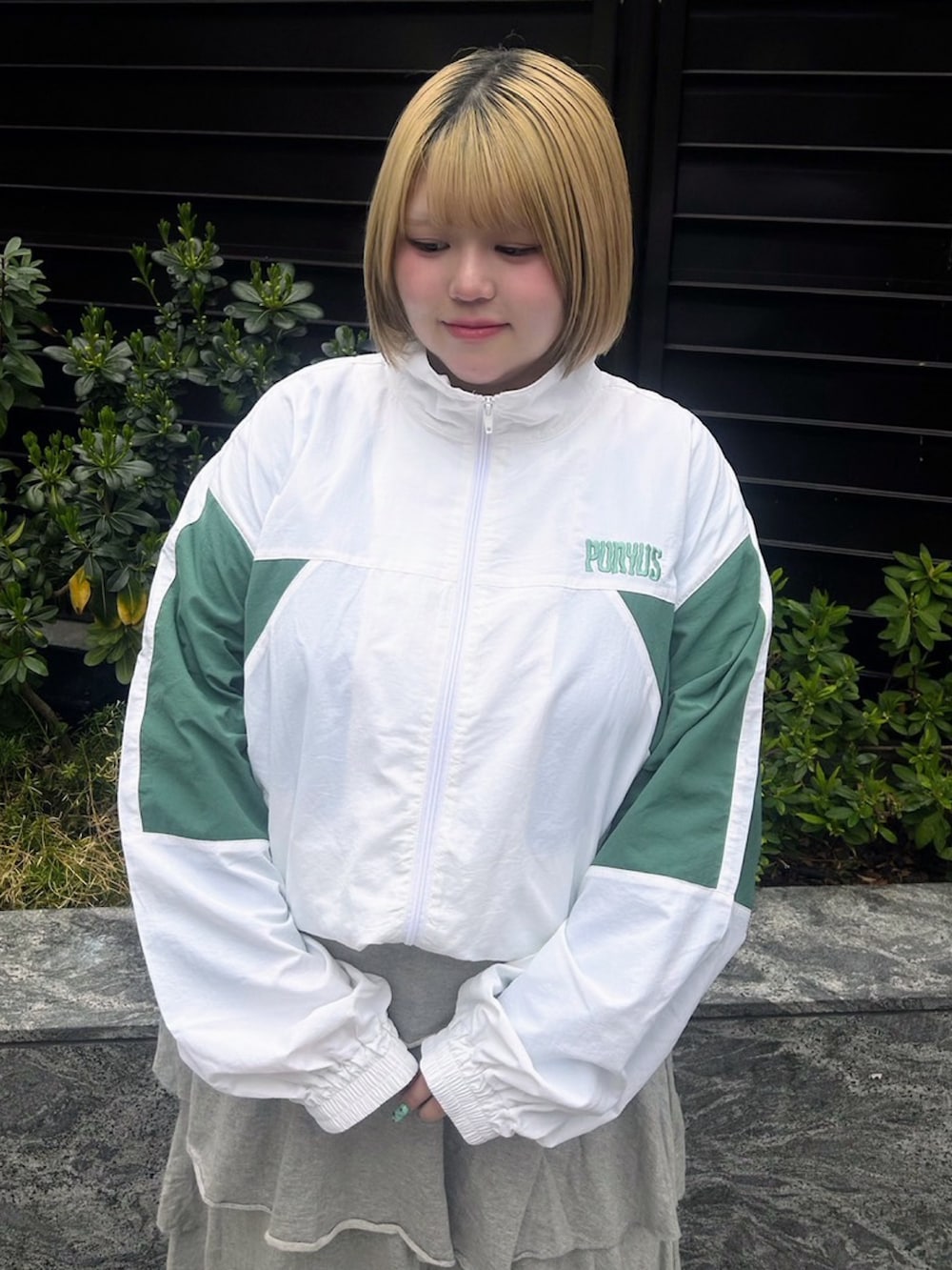 グレー系のスカート、ホワイト系のナイロンジャケットを着用したレディースの春コーディネートの5枚目の写真