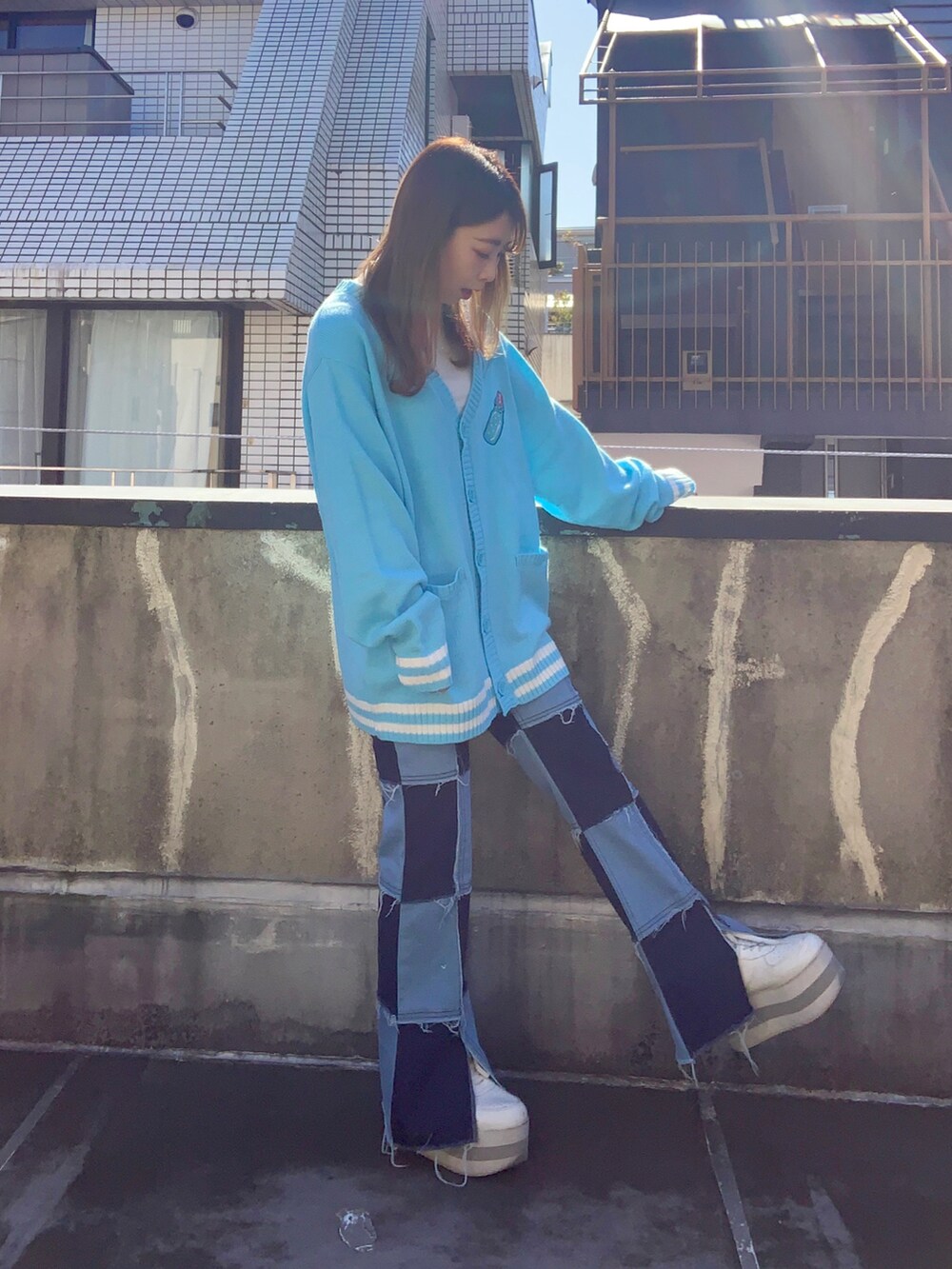 ブルー系のカーディガン/ボレロ、ブルー系のデニムパンツ、ホワイト系のスニーカーを着用したレディースの秋コーディネートの2枚目の写真