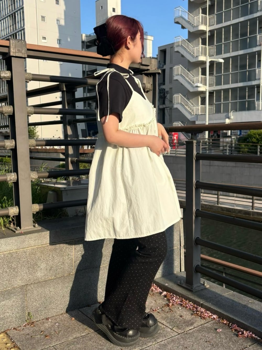 ブラック系のデニムパンツ、ホワイト系のワンピース、ブラック系のTシャツ/カットソーを着用したレディースの春コーディネートの3枚目の写真
