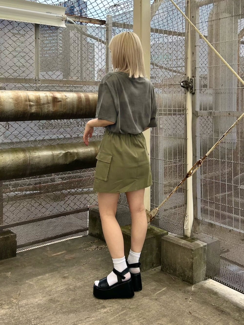 グリーン系のスカート、ブラック系のTシャツ/カットソー、ブラック系のサンダルを着用したレディースの夏コーディネートの2枚目の写真