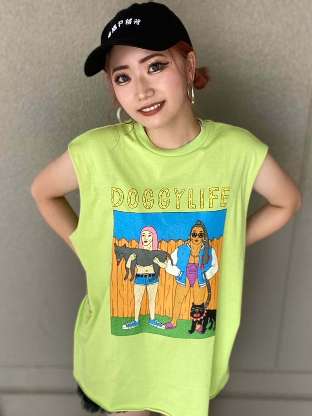 グリーン系のタンクトップ、ブラック系のデニムパンツ、ブラック系のキャップを着用したレディースの夏コーディネートの2枚目の写真