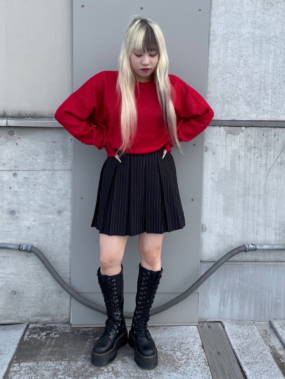 レッド系のニット/セーター、ブラック系のスカートを着用したレディースの秋コーディネートの2枚目の写真