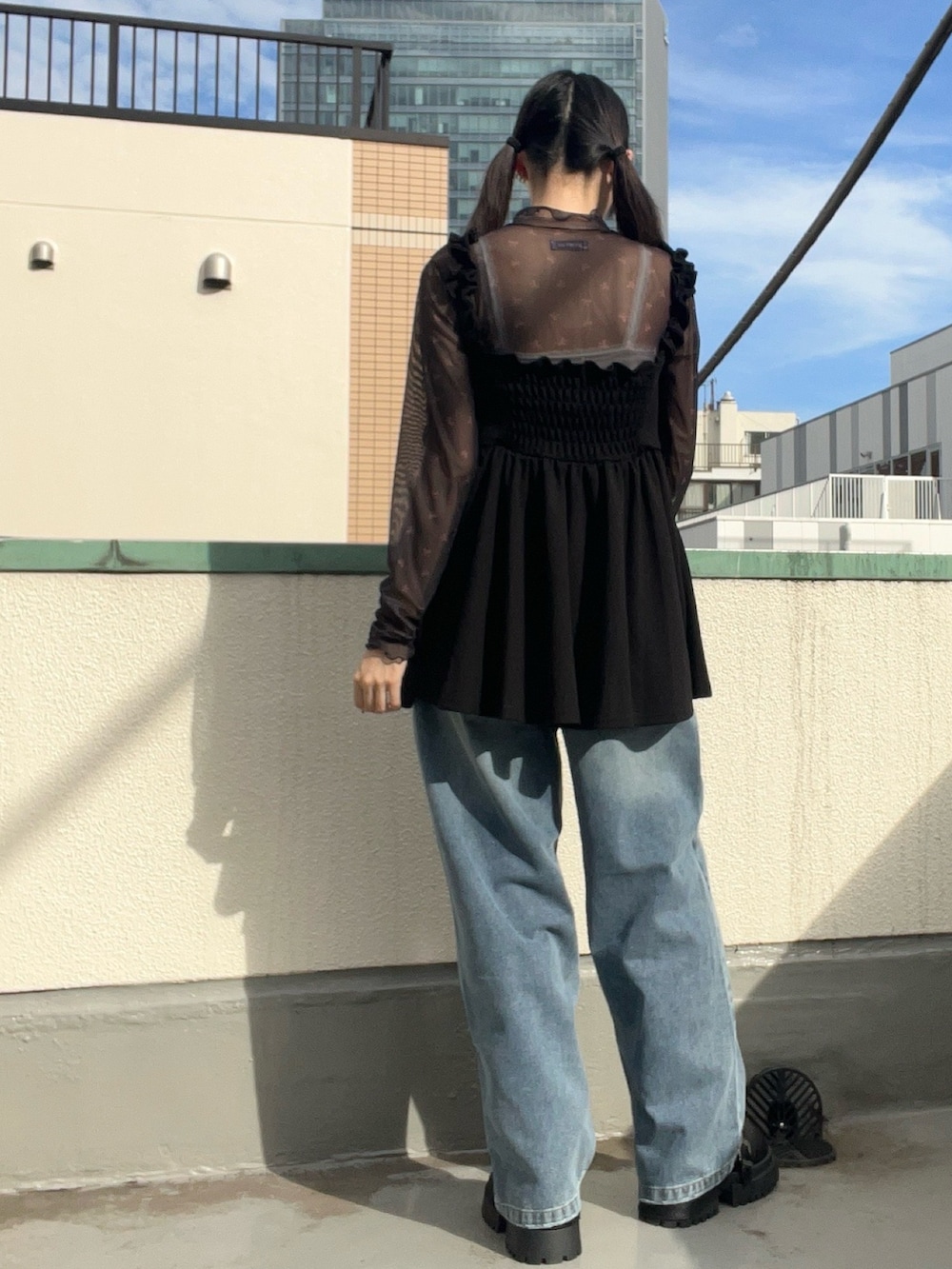 ブルー系のデニムパンツ、ブラック系のワンピース、ブラック系のTシャツ/カットソーを着用したレディースの秋コーディネートの5枚目の写真