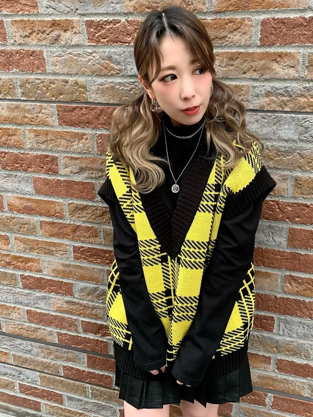 ブラック系のTシャツ/カットソー、イエロー系のベスト、ブラック系のスカートを着用したレディースの冬コーディネートの2枚目の写真