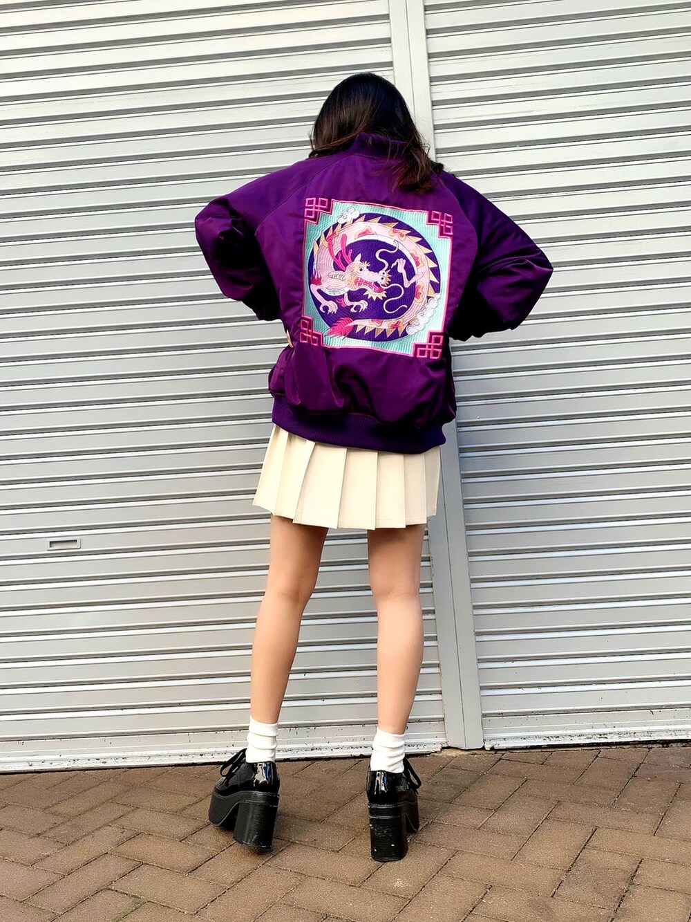 ブラック系のTシャツ/カットソー、パープル系のブルゾン、ホワイト系のスカートを着用したレディースの冬コーディネートの2枚目の写真