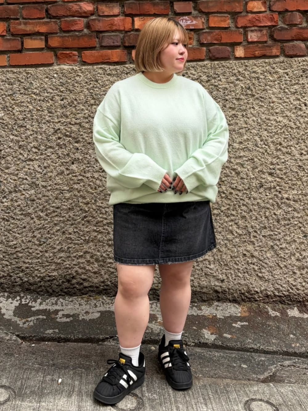 ブラック系のデニムスカート、グリーン系のニット/セーターを着用したレディースの冬コーディネートの2枚目の写真