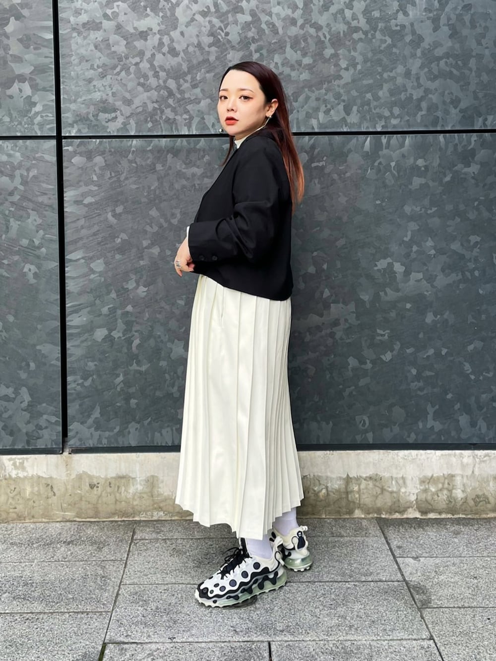 ブラック系のテーラードジャケット、ホワイト系のスカート、ホワイト系のTシャツ/カットソーを着用したレディースの冬コーディネートの2枚目の写真