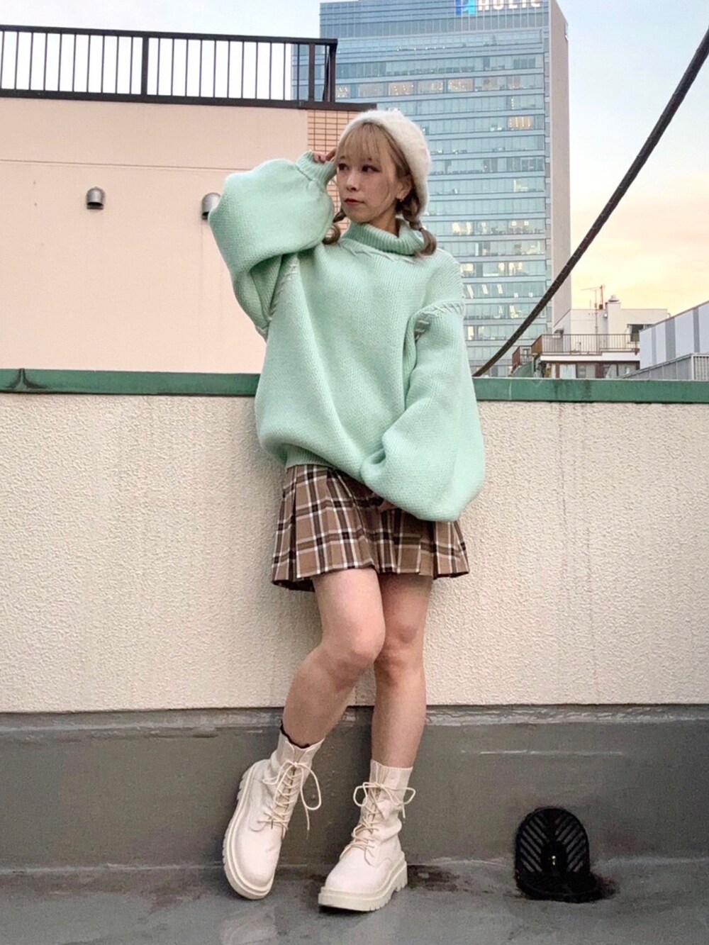 グリーン系のニット/セーター、ベージュ系のスカート、ホワイト系のハンチング/ベレー帽を着用したレディースの冬コーディネートの3枚目の写真