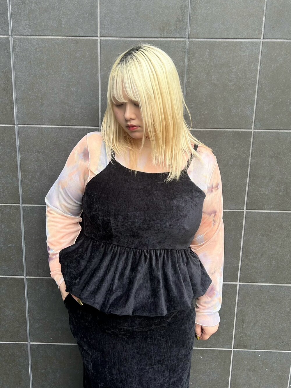 ブラック系のスカート、ブラック系のチュニック、オレンジ系のTシャツ/カットソーを着用したレディースの冬コーディネートの4枚目の写真
