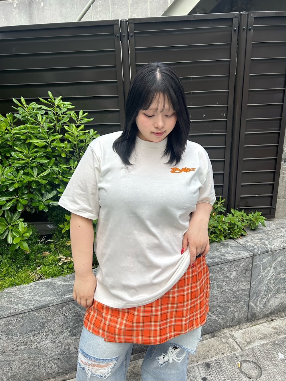 ブルー系のデニムパンツ、オレンジ系のスカート、ホワイト系のTシャツ/カットソーを着用したレディースの春コーディネートの3枚目の写真