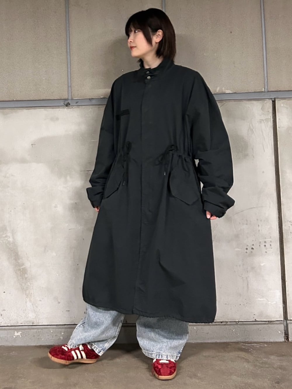 ブラック系のモッズコート、ブルー系のデニムパンツ、レッド系のカーディガン/ボレロを着用したレディースの春コーディネートの4枚目の写真