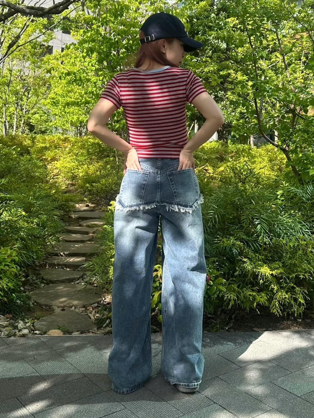 ブルー系のデニムパンツ、レッド系のTシャツ/カットソー、ブルー系のキャップを着用したレディースの春コーディネートの4枚目の写真