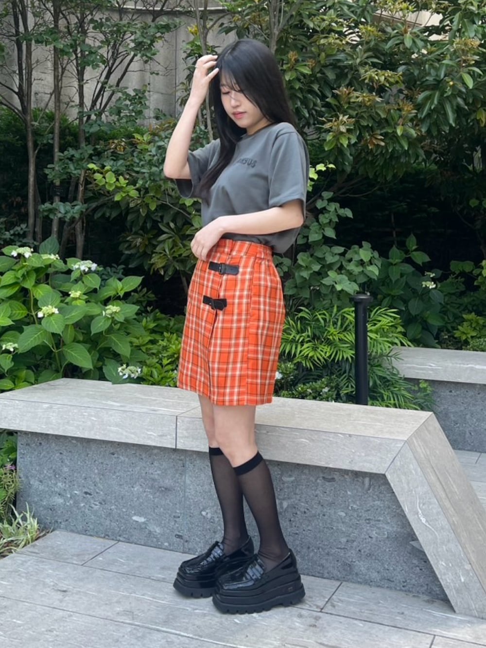 オレンジ系のスカート、ブラック系のTシャツ/カットソーを着用したレディースの春コーディネートの2枚目の写真