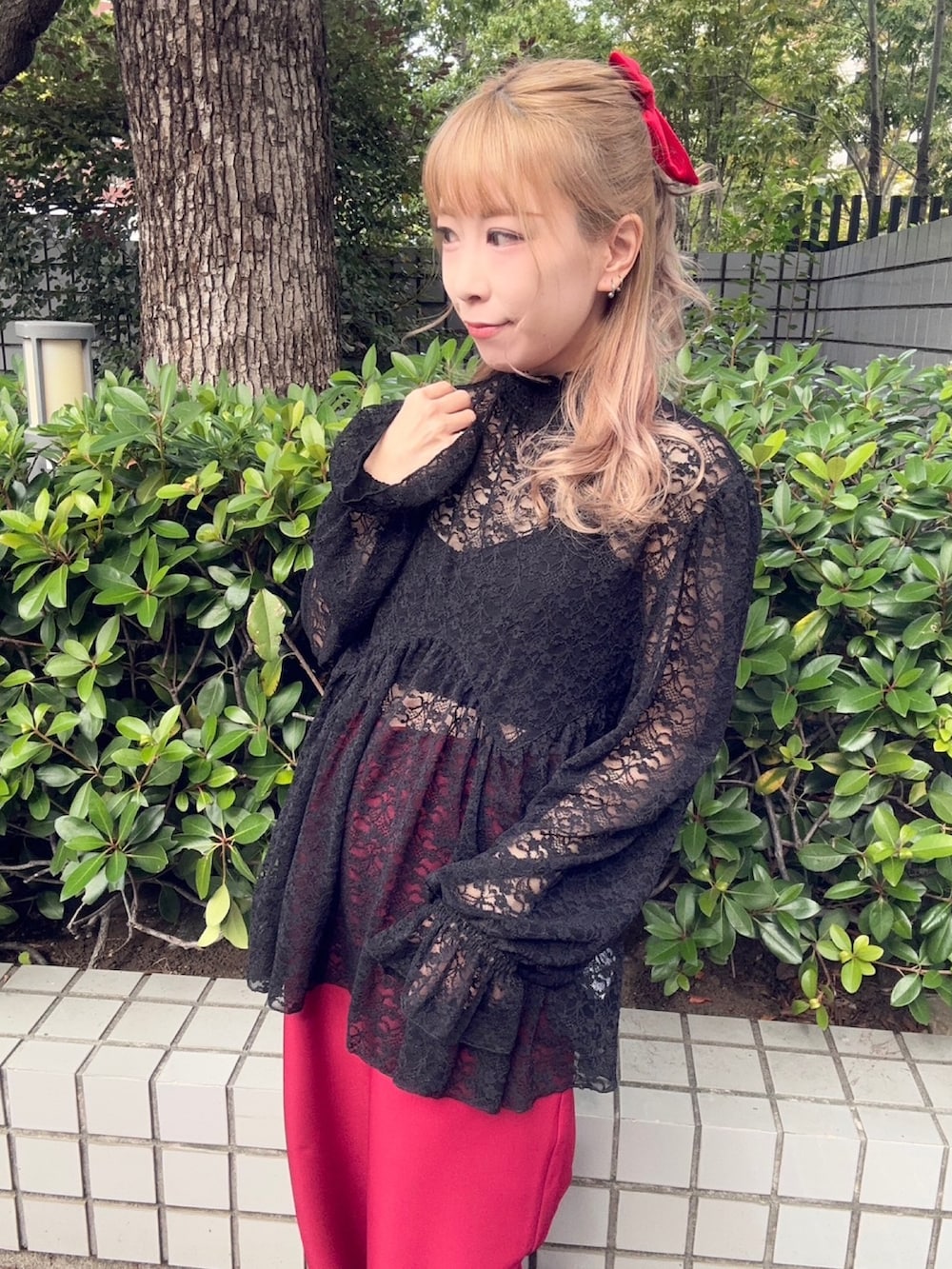 レッド系のスラックス、ブラック系のTシャツ/カットソー、レッド系のシュシュを着用したレディースの秋コーディネートの2枚目の写真