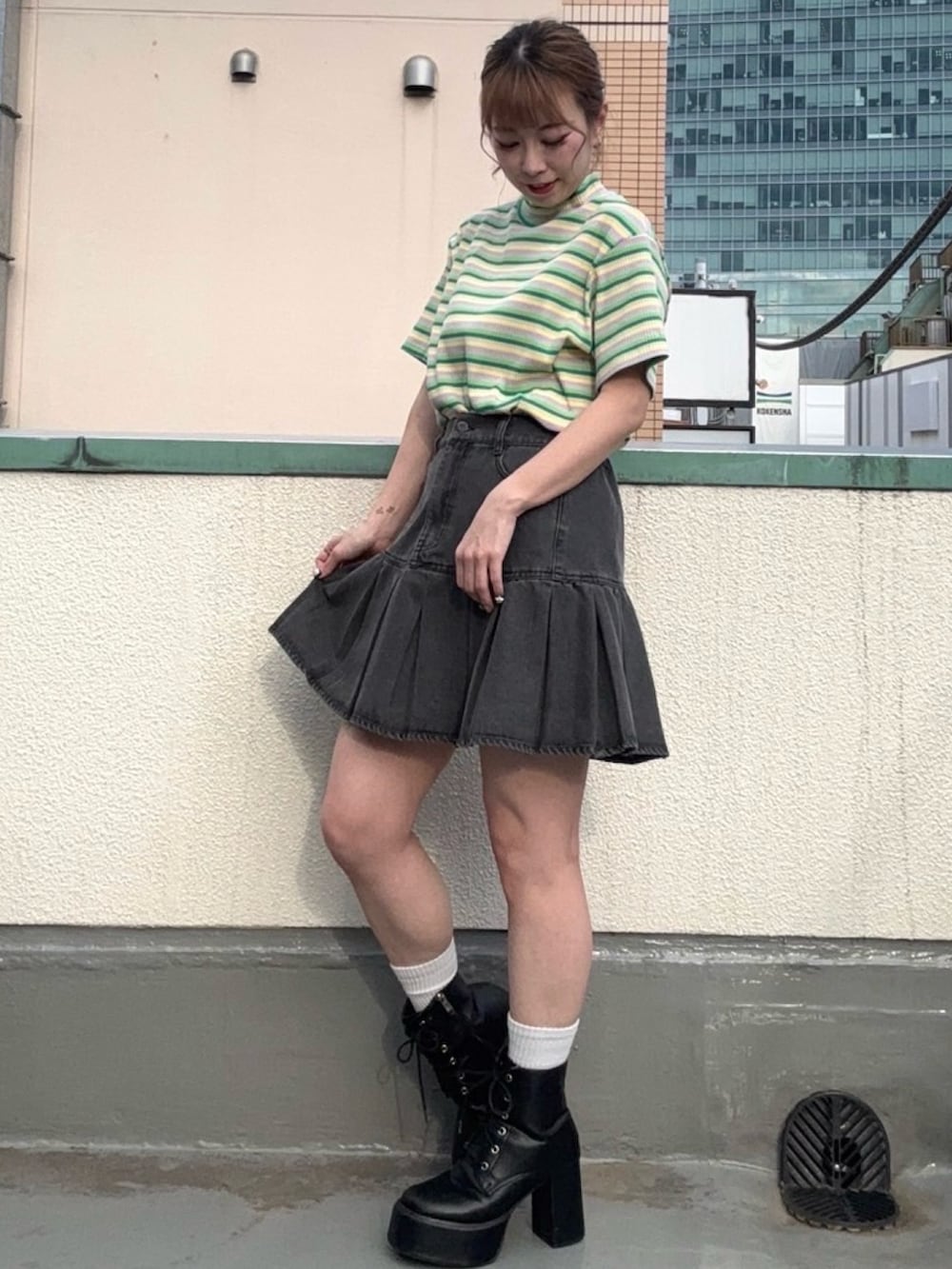 ブラック系のデニムスカート、グリーン系のTシャツ/カットソーを着用したレディースの春コーディネートの2枚目の写真