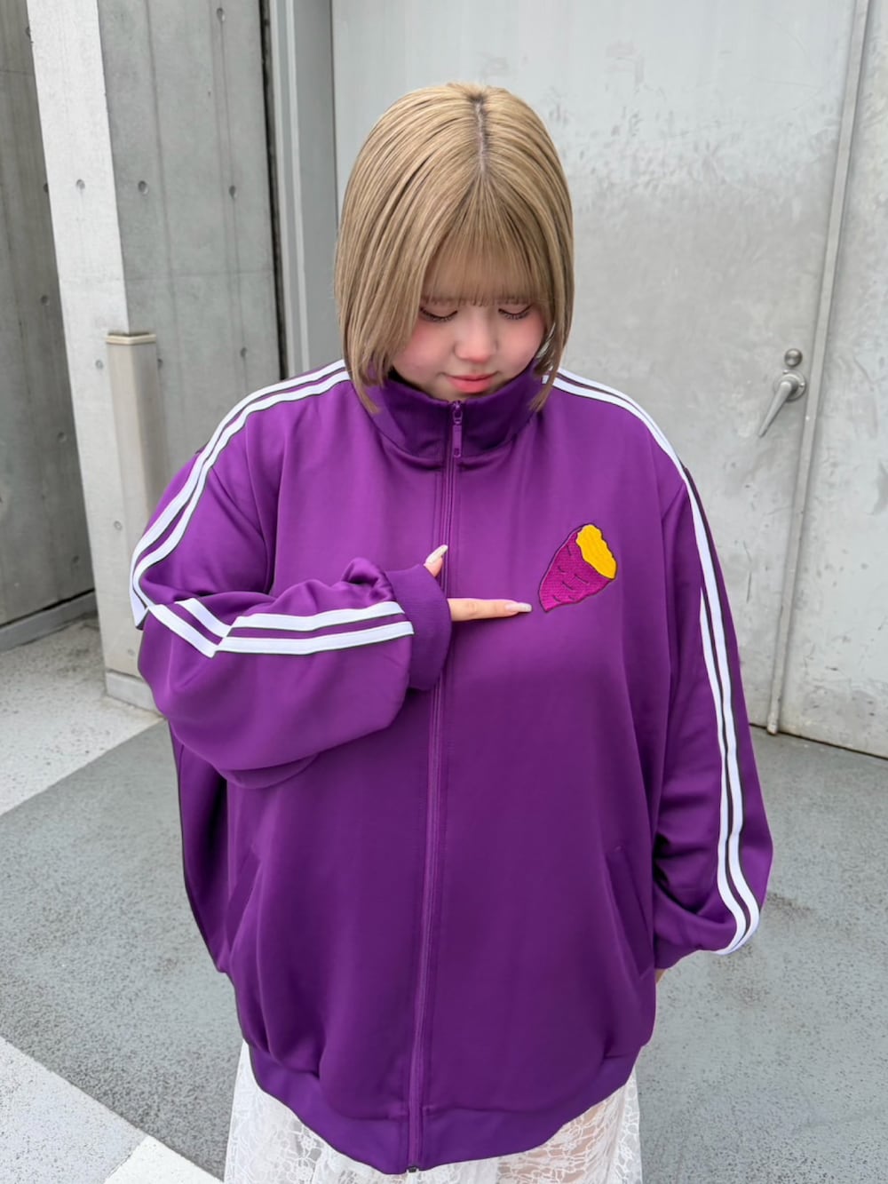パープル系のジャージ、ホワイト系のスカートを着用したレディースの秋コーディネートの4枚目の写真