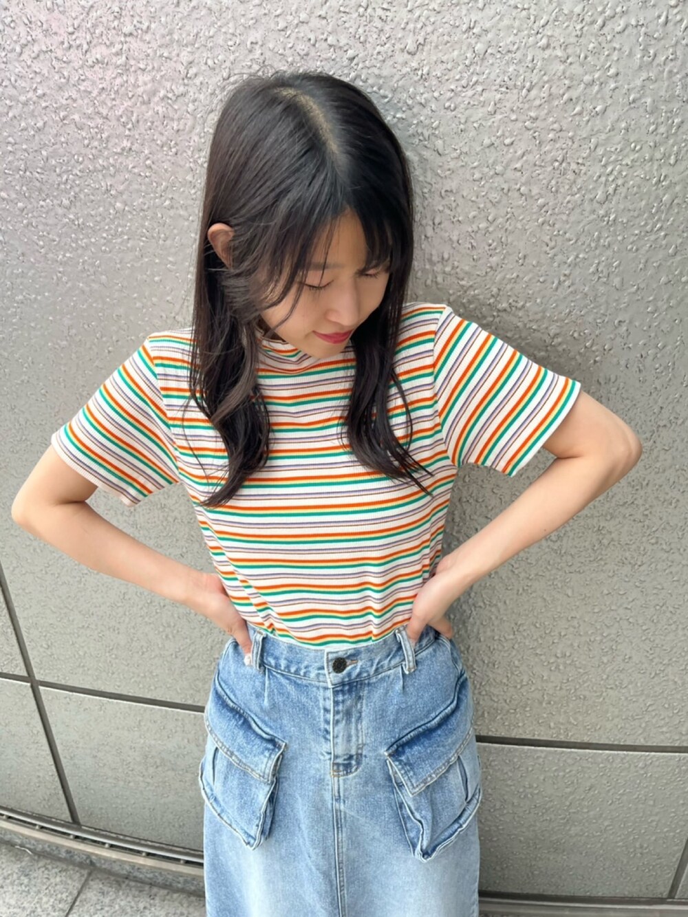 オレンジ系のTシャツ/カットソー、ブルー系のデニムスカートを着用したレディースの春コーディネートの3枚目の写真