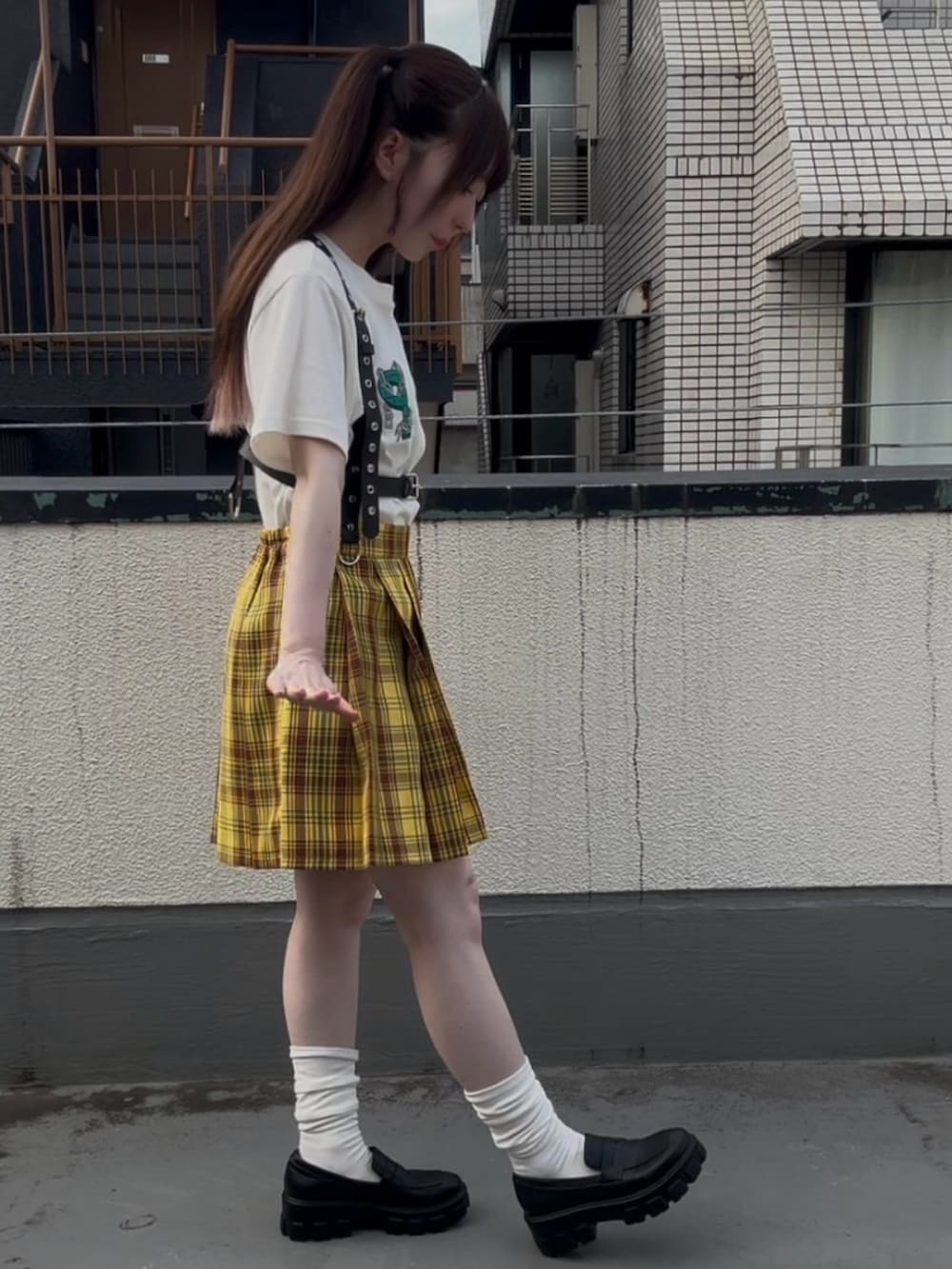イエロー系のスカート、ホワイト系のTシャツ/カットソー、ブラック系のベルトを着用したレディースの秋コーディネートの3枚目の写真