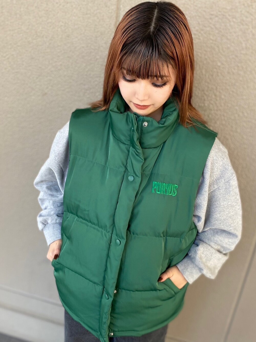 グリーン系のダウンベスト、グレー系のパーカー、ブラック系のデニムパンツを着用したレディースの秋コーディネートの2枚目の写真