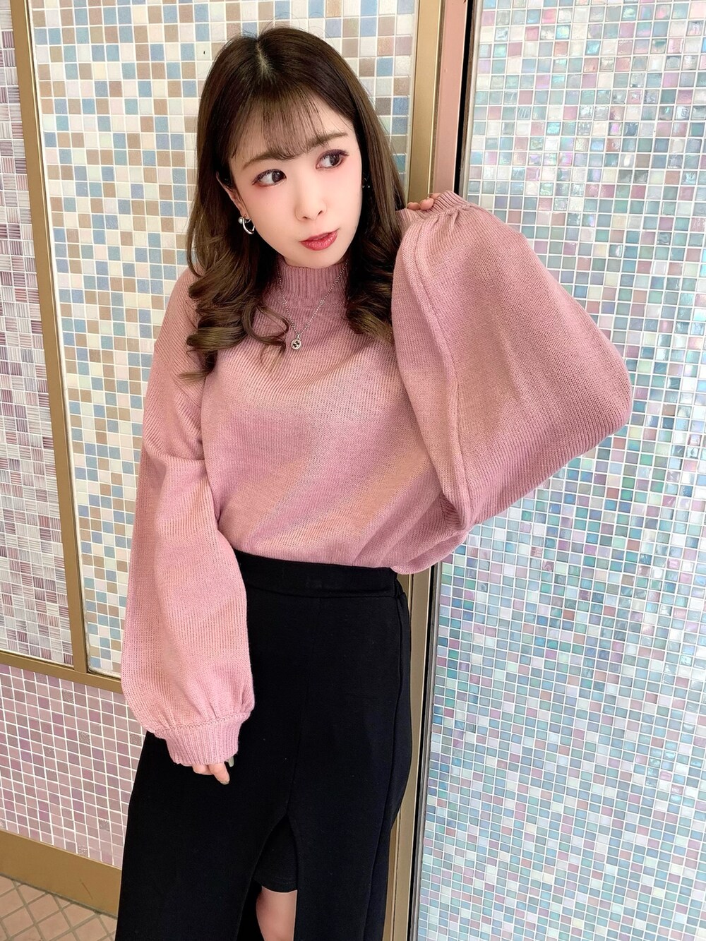 ピンク系のニット/セーター、ブラック系のスカート、ブラック系のブーツを着用したレディースの秋コーディネートの2枚目の写真