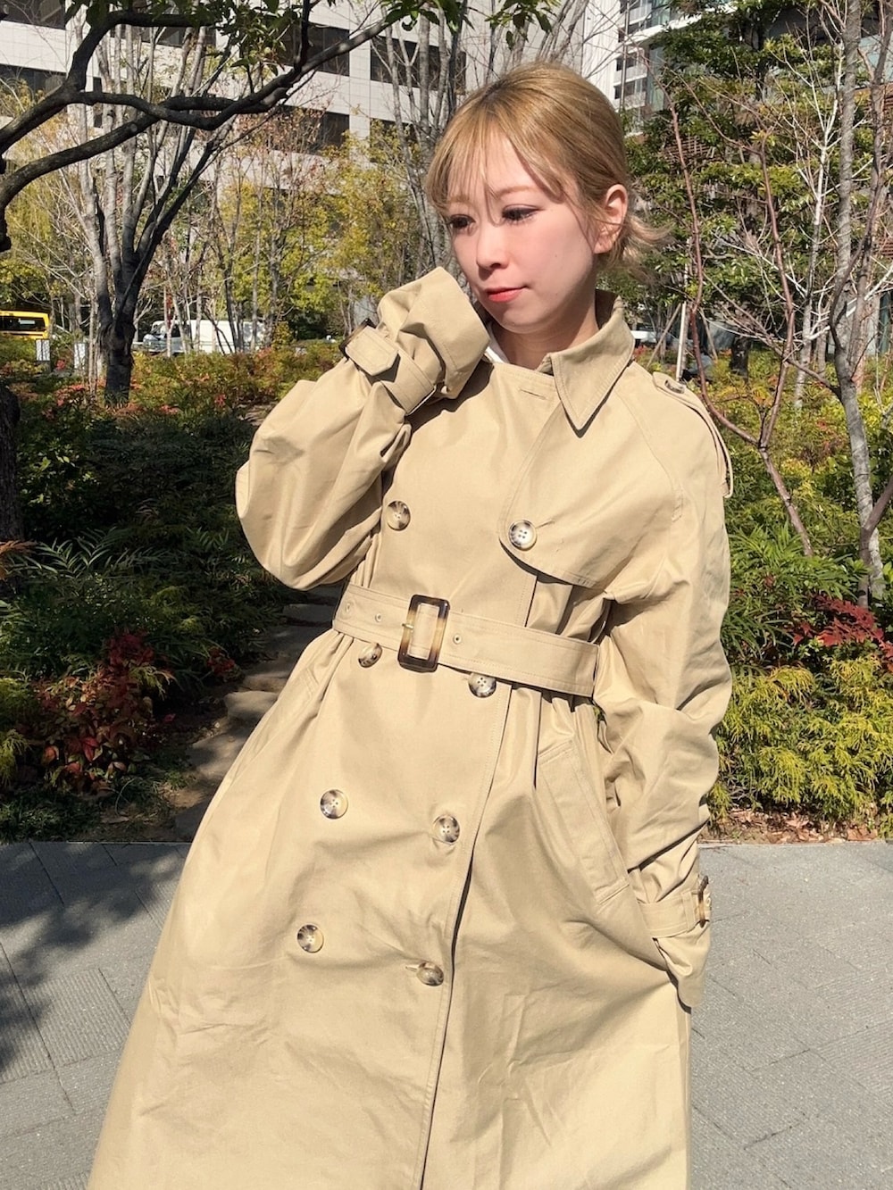 ベージュ系のトレンチコート、ベージュ系のスカートを着用したレディースの春コーディネートの3枚目の写真