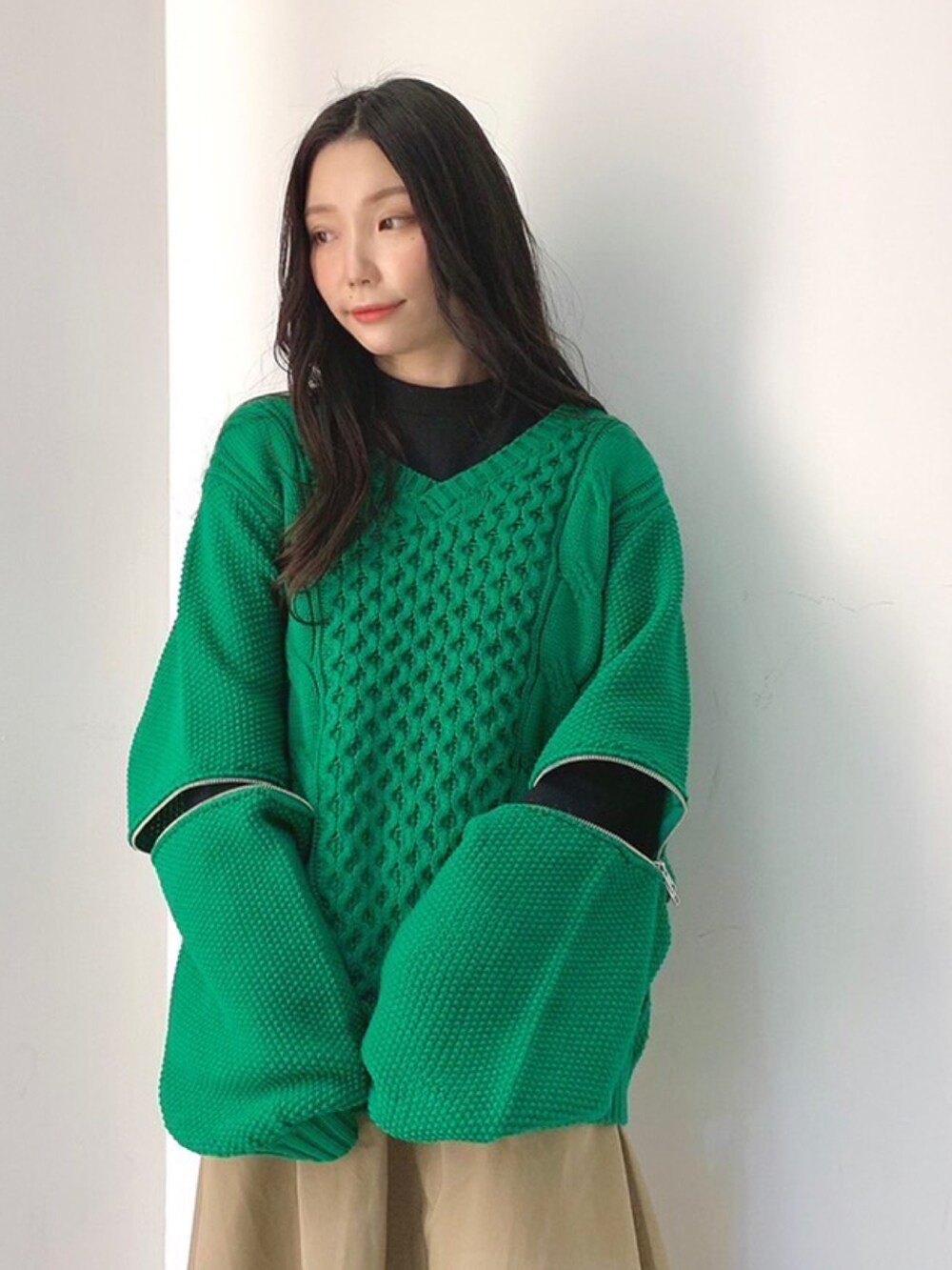 ブラック系のTシャツ/カットソー、グリーン系のニット/セーター、ベージュ系のスカートを着用したレディースの冬コーディネートの2枚目の写真