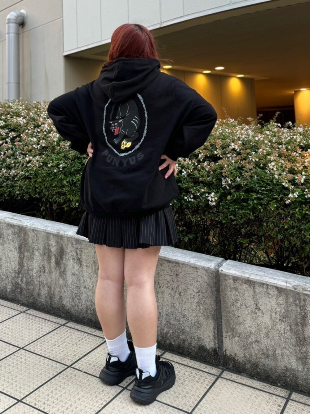 ブラック系のパーカー、ブラック系のスカートを着用したレディースの秋コーディネートの2枚目の写真