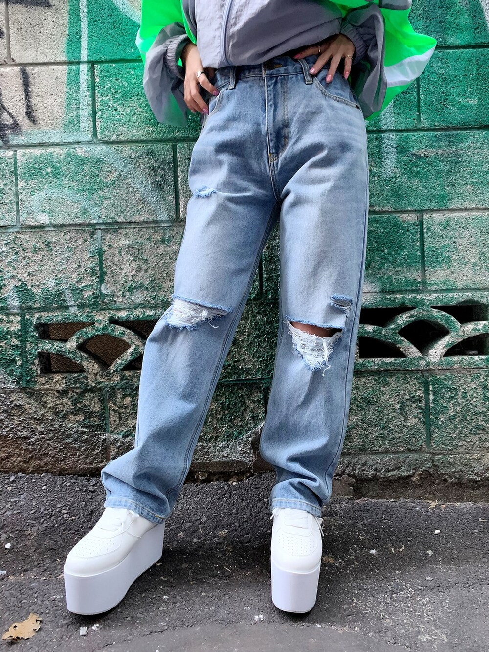 グレー系のナイロンジャケット、ブルー系のデニムパンツ、ホワイト系のスニーカーを着用したレディースの冬コーディネートの3枚目の写真