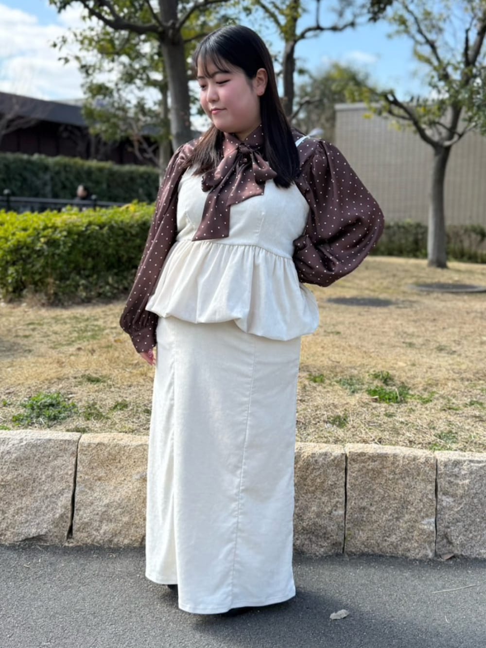 ホワイト系のスカート、ホワイト系のチュニック、ブラウン系のシャツ/ブラウスを着用したレディースの春コーディネートの2枚目の写真