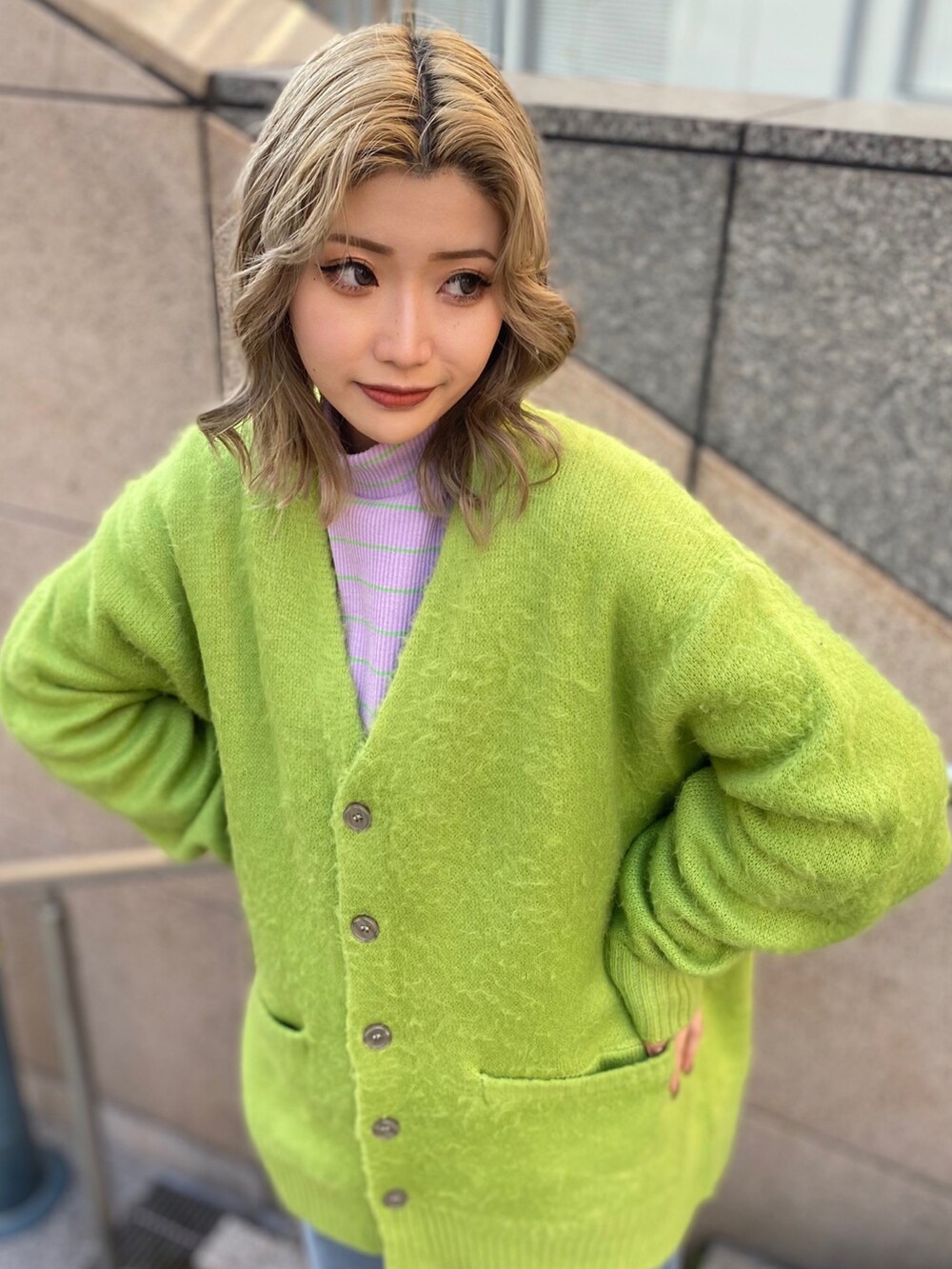 グリーン系のカーディガン/ボレロ、パープル系のTシャツ/カットソー、ブルー系のデニムパンツを着用したレディースの冬コーディネートの3枚目の写真