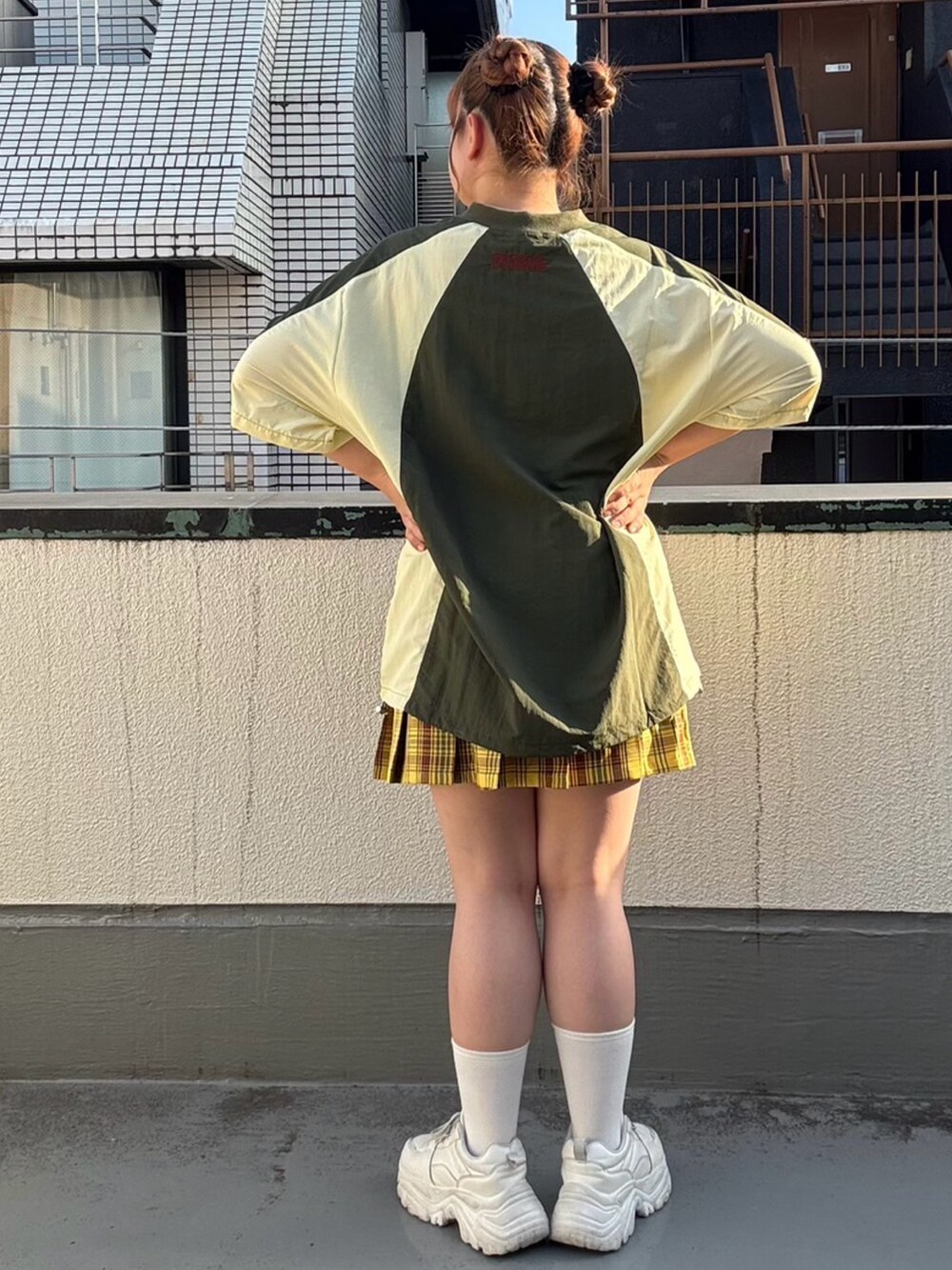 グリーン系のTシャツ/カットソー、イエロー系のスカートを着用したレディースの秋コーディネートの3枚目の写真