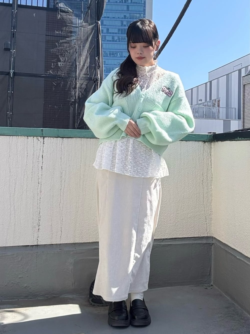 ホワイト系のスカート、ホワイト系のTシャツ/カットソー、グリーン系のカーディガン/ボレロを着用したレディースの春コーディネートの2枚目の写真