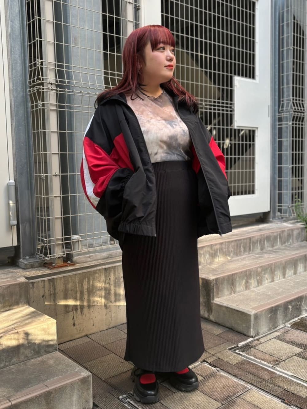 ブラック系のスカート、ブラック系のナイロンジャケット、ブラウン系のTシャツ/カットソーを着用したレディースの秋コーディネートの3枚目の写真