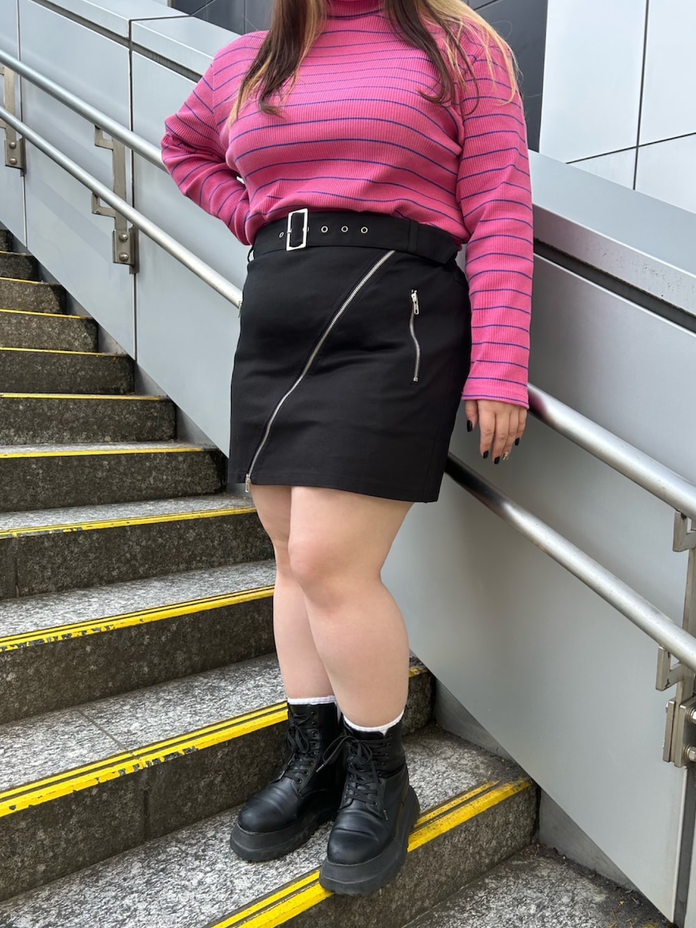 ピンク系のTシャツ/カットソー、ブラック系のスカート、ブラック系のブーツを着用したレディースの春コーディネートの2枚目の写真