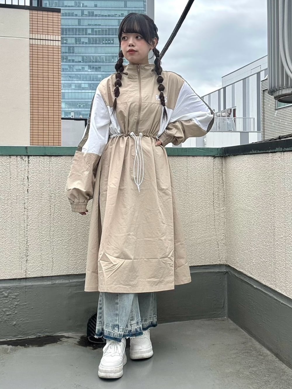 ベージュ系のワンピース、ブルー系のデニムパンツを着用したレディースの春コーディネートの2枚目の写真