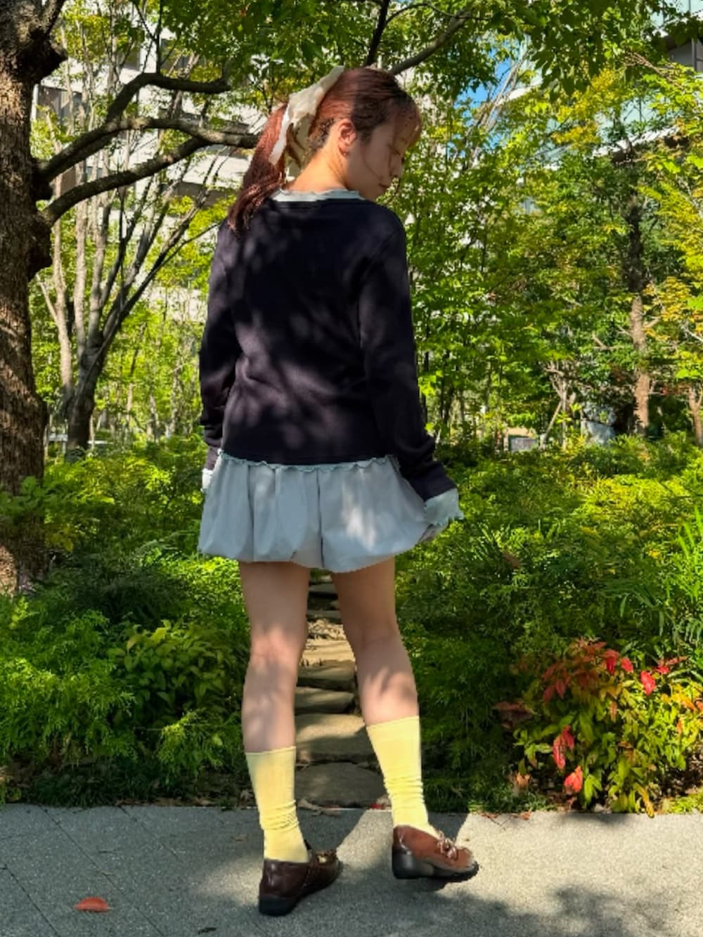 グレー系のスカート、ブルー系のTシャツ/カットソー、ブルー系のカーディガン/ボレロを着用したレディースの秋コーディネートの3枚目の写真