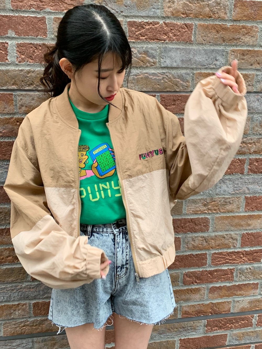 ベージュ系のナイロンジャケット、ブルー系のデニムパンツ、グリーン系のTシャツ/カットソーを着用したレディースの春コーディネートの2枚目の写真