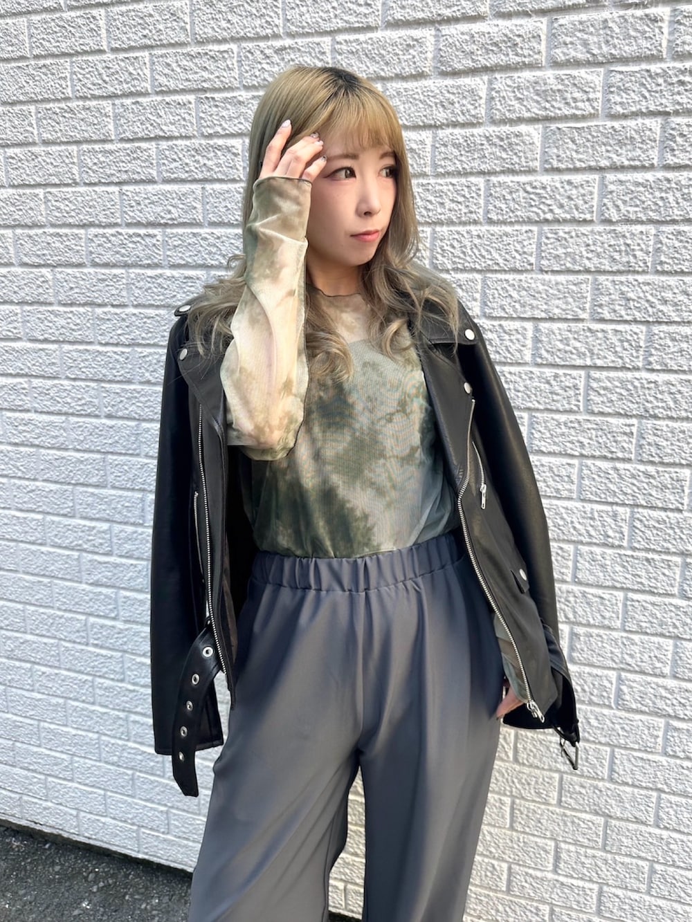 グレー系のスラックス、ブラック系のライダースジャケット、グリーン系のTシャツ/カットソーを着用したレディースの秋コーディネートの2枚目の写真