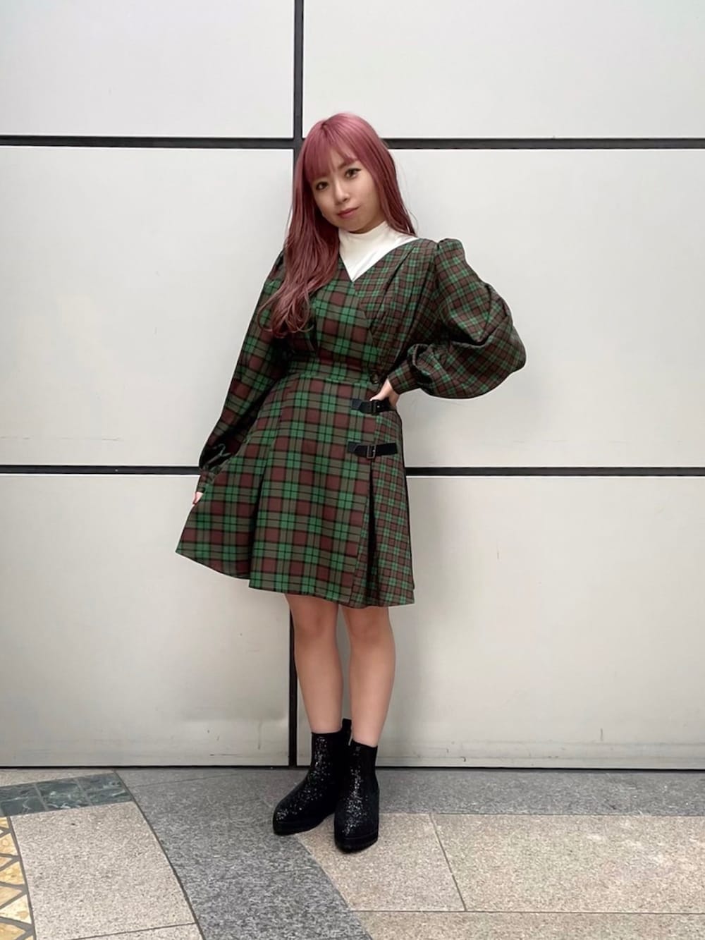 グリーン系のワンピース、ブラック系のライダースジャケット、ホワイト系のニット/セーターを着用したレディースの秋コーディネートの2枚目の写真