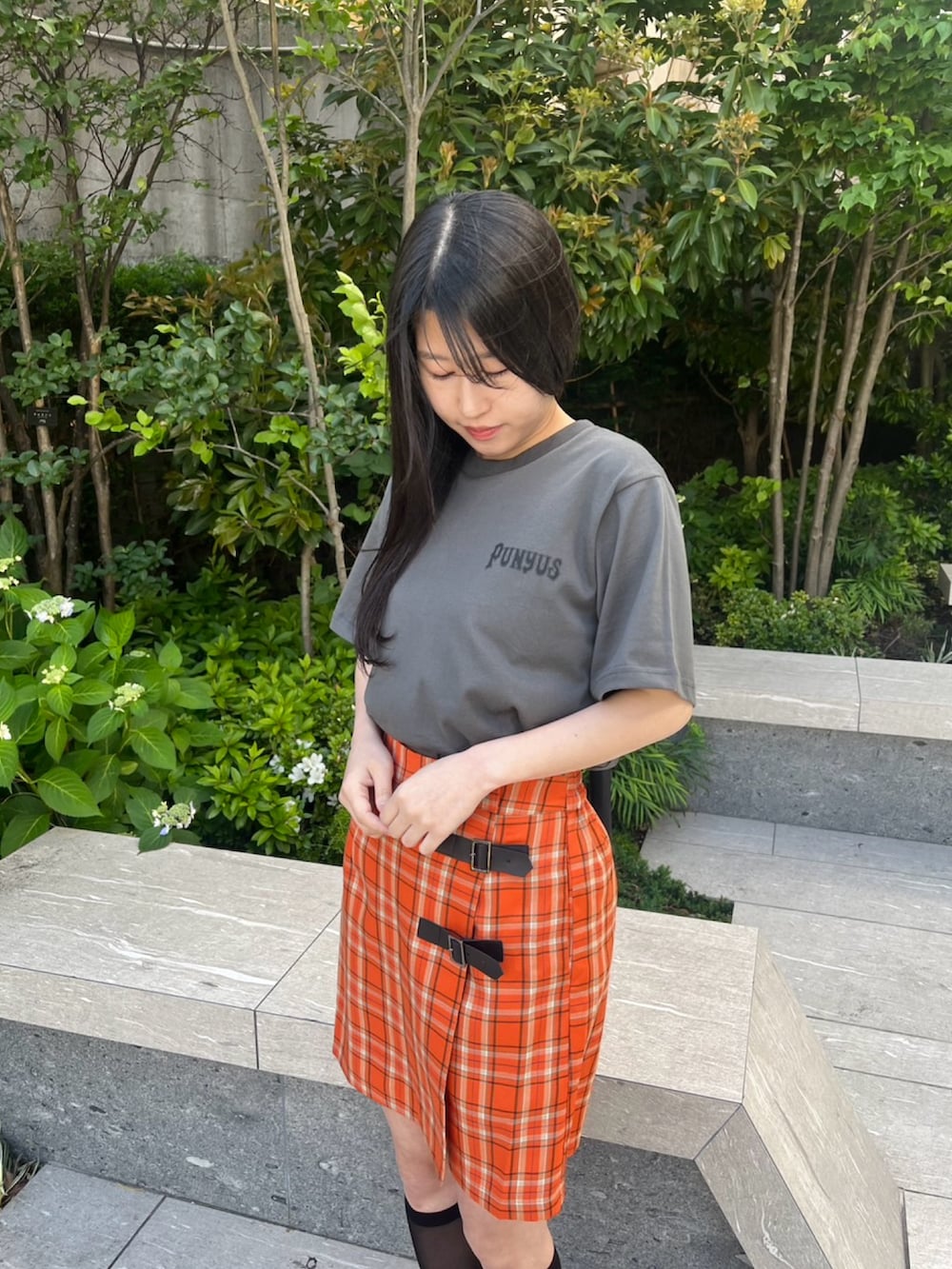 オレンジ系のスカート、ブラック系のTシャツ/カットソーを着用したレディースの春コーディネートの4枚目の写真