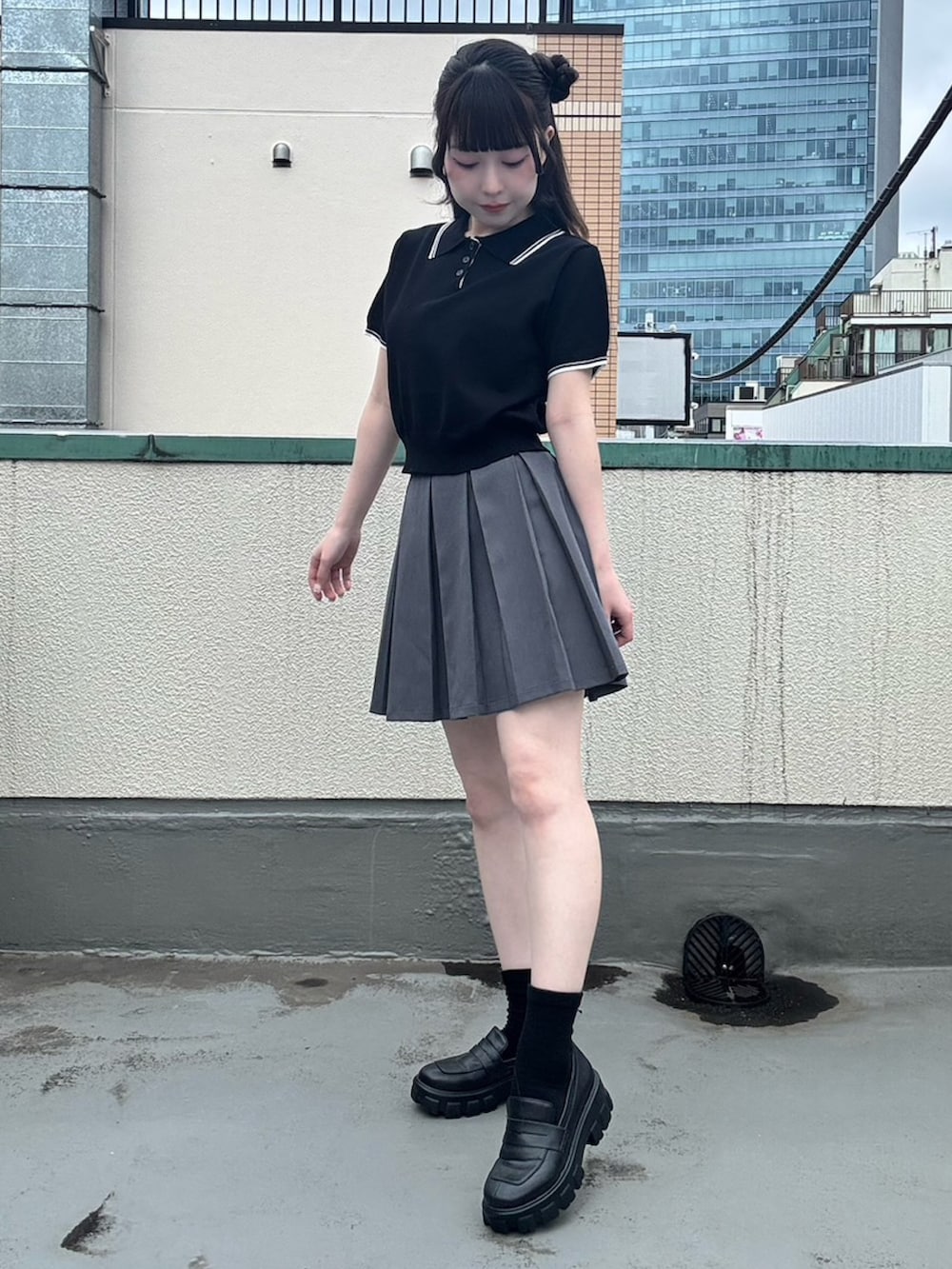 グレー系のスカート、ブラック系のポロシャツを着用したレディースの夏コーディネートの2枚目の写真